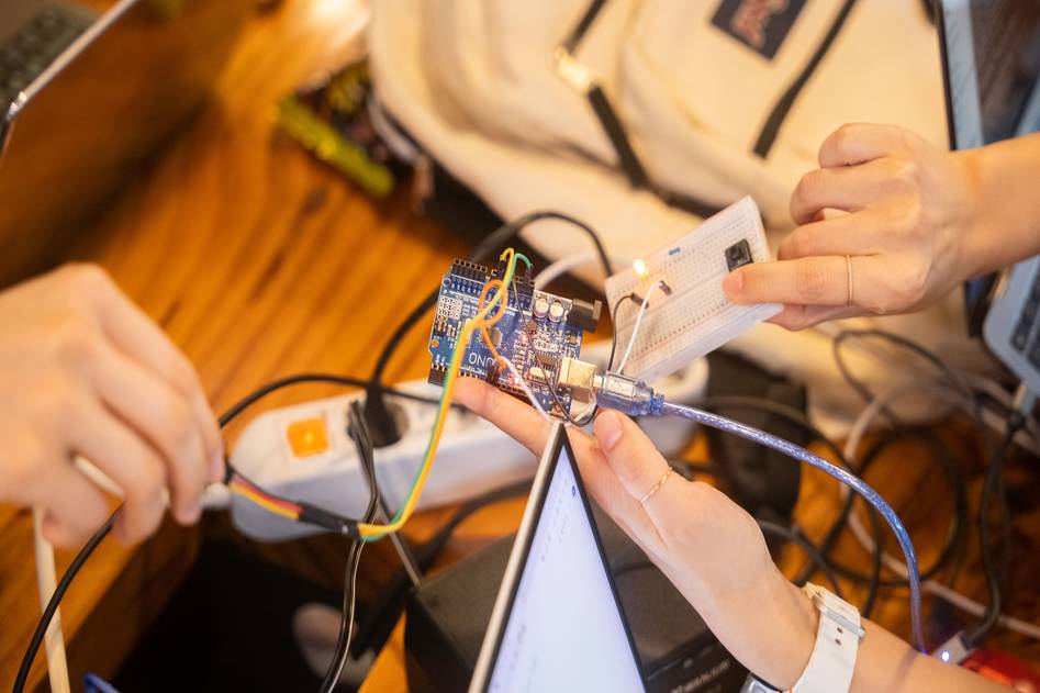 Embedded systems developer working with microcontroller board and oscilloscope